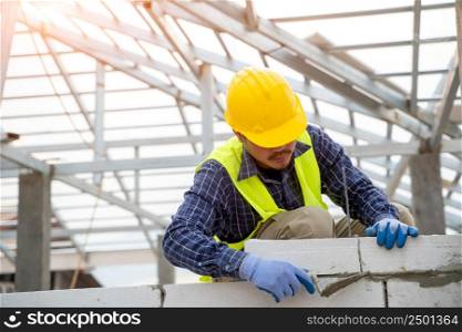 Engineer applying putty or tile glue to with lightweight concrete blocks,On construction site.