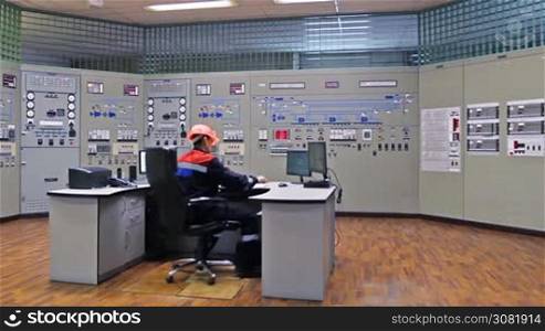 engineer approaches power supply shield, checks circuit and returns to workplace, pan shot