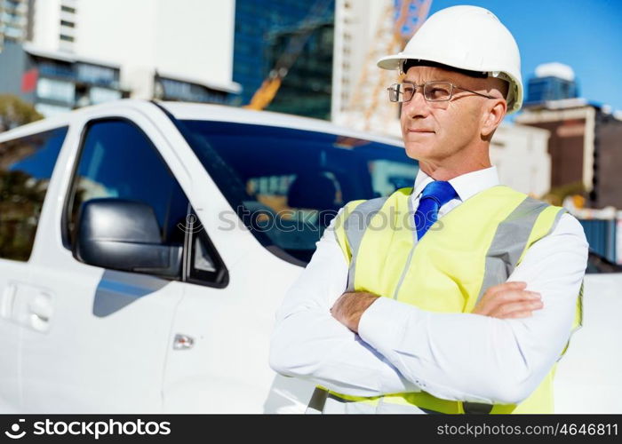 Engineer builder at construction site. Engineer builder wearing safety vest at construction site next to white van