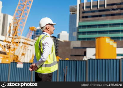 Engineer builder at construction site. Engineer builder wearing safety vest at construction site