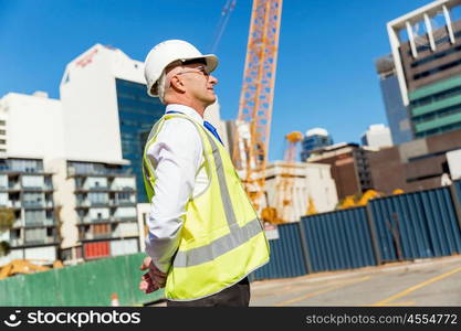 Engineer builder at construction site. Engineer builder wearing safety vest at construction site