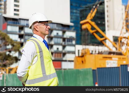 Engineer builder at construction site. Engineer builder wearing safety vest at construction site