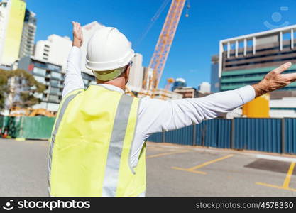 Engineer builder at construction site. Engineer builder wearing safety vest at construction site