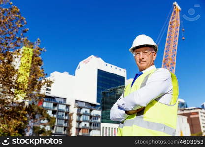 Engineer builder at construction site. Engineer builder wearing safety vest at construction site