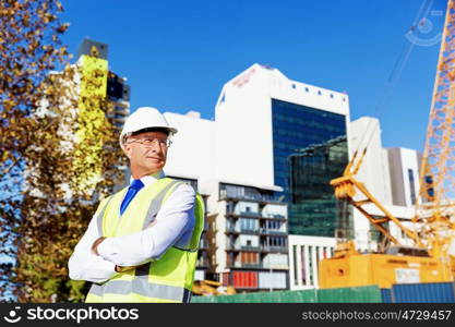 Engineer builder at construction site. Engineer builder wearing safety vest at construction site