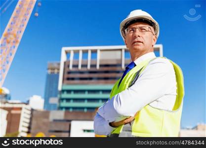 Engineer builder at construction site. Engineer builder wearing safety vest at construction site