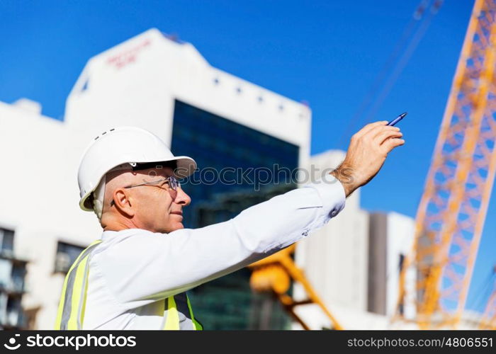 Engineer builder at construction site. Engineer builder wearing safety vest at construction site