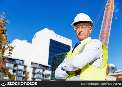 Engineer builder at construction site. Engineer builder wearing safety vest at construction site