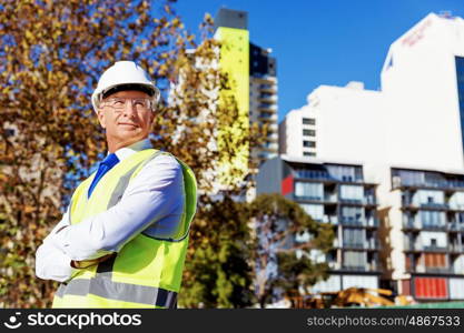 Engineer builder at construction site. Engineer builder wearing safety vest at construction site