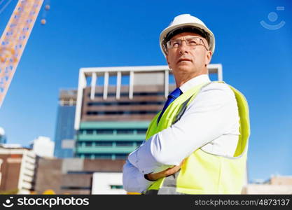 Engineer builder at construction site. Engineer builder wearing safety vest at construction site