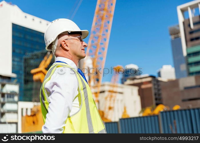 Engineer builder at construction site. Engineer builder wearing safety vest at construction site