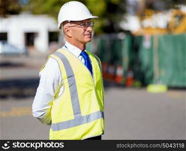Engineer builder at construction site. Engineer builder wearing safety vest at construction site