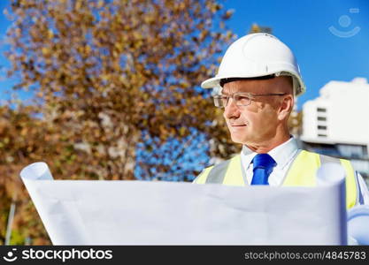 Engineer builder at construction site. Engineer builder wearing safety vest with blueprint at construction site