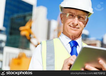 Engineer builder at construction site. Engineer builder wearing safety vest with notepad at construction site