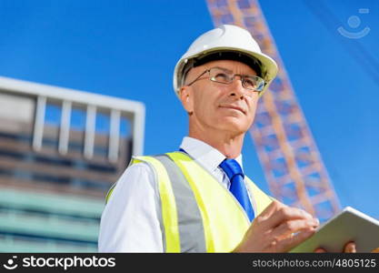 Engineer builder at construction site. Engineer builder wearing safety vest with notepad at construction site