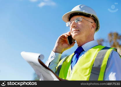 Engineer builder at construction site. Engineer builder wearing safety vest with notepad at construction site