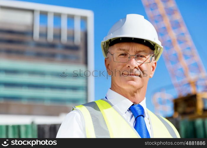 Engineer builder at construction site. Engineer builder wearing safety vest with notepad at construction site