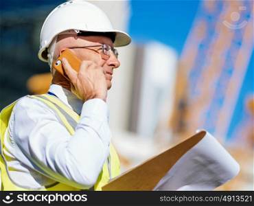 Engineer builder at construction site. Engineer builder wearing safety vest with notepad at construction site
