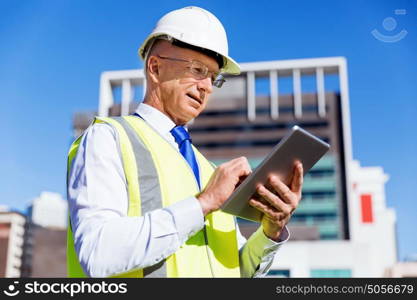 Engineer builder at construction site. Engineer builder wearing safety vest with notepad at construction site