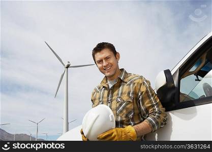 Engineer by car at wind farm, portrait