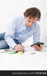 Engineer calculating the measurements of technical drawings, making notes with a pencil