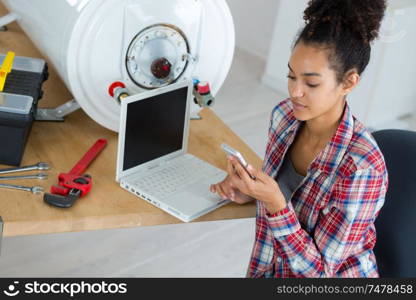 engineer checking pc and phone while fixing a boiler