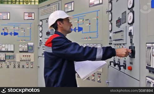 engineer checks thermal sensors and writes into registry near main control panel of gas compressor station