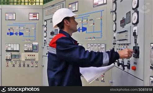 engineer checks thermal sensors and writes into registry near main control panel of gas compressor station