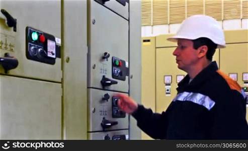 engineer comes, unlocks and activates electrical equipment from control panel, closeup