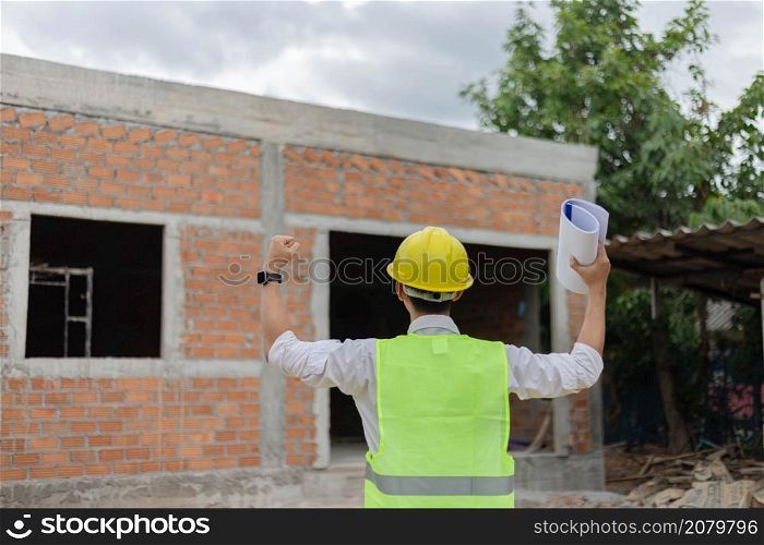 engineer concept The constructing guy looking at the construction site and raising his hands for expressing his rejoice moment.