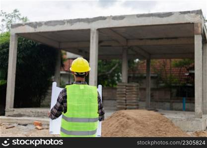 engineer concept The constructing manipulator who wears a hard yellow hat, dark-toned plaid blouse and soft green vest looking at the processing building construction.