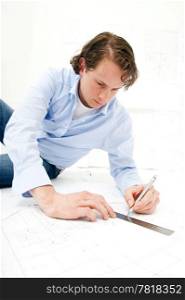 Engineer drawing a line on a set of technical drawings using a pencil and a ruler
