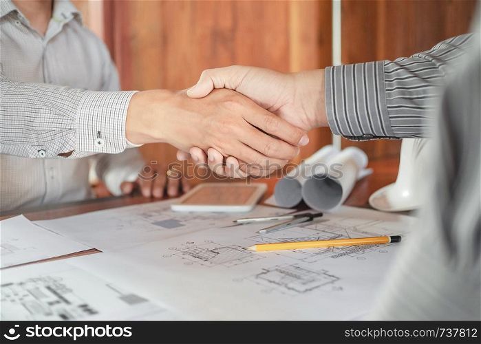 Engineer handshake together with blueprint in workplace.