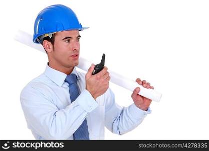 Engineer holding a rolled-up plan and speaking into a walkie-talkie