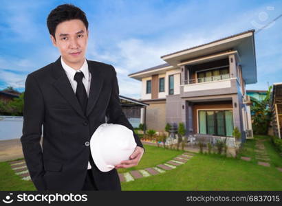 engineer holding helmet with modern house background