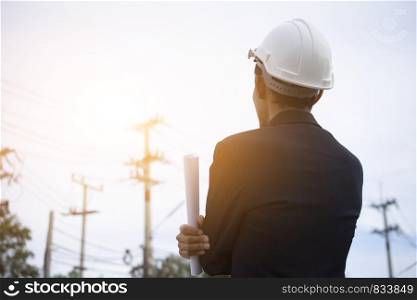 Engineer holding paper electric pole background