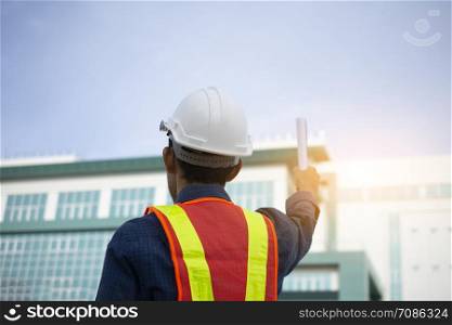 Engineer holding paper plan against building sky background