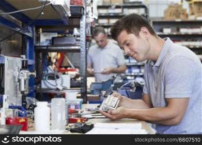 Engineer In Factory Measuring Component At Work Bench Using Micrometer