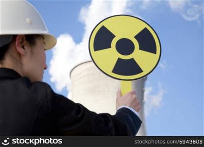 Engineer in front of cooling towers with sign