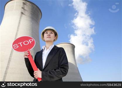 Engineer in front of cooling towers with stop sign