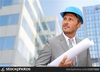 Engineer in front of modern building with plan