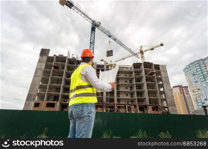Engineer in hardhat looking at building under construction