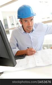 Engineer in office working on construction plan