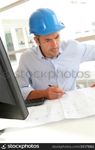 Engineer in office working on construction plan