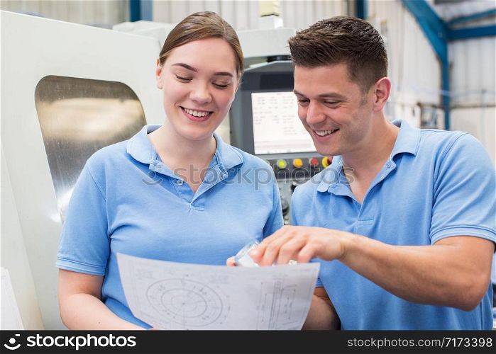 Engineer Instructing Female Apprentice On Use Of CNC Machine