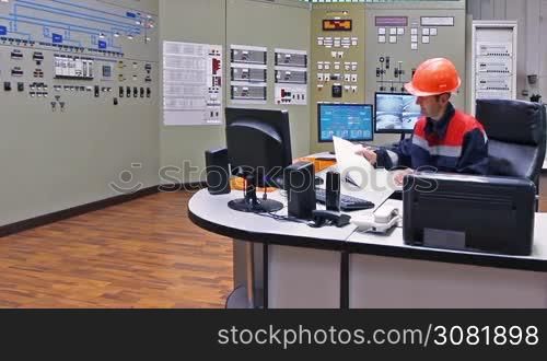 engineer looks into work log and writes in it at main control panel of gas compressor station