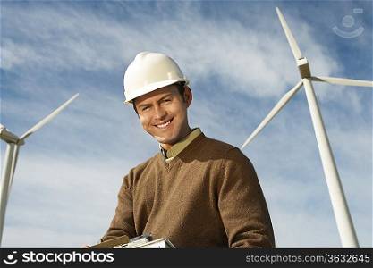 Engineer near wind turbines at wind farm, portrait