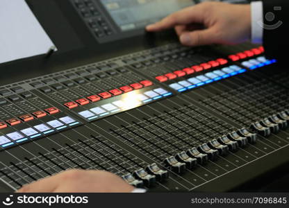 Engineer operating the controls of sound mixing board. Close up view. Selective focus.