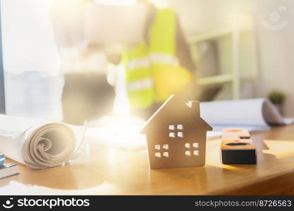 engineer planing and checking on blueprint on table background of small model house, real estate concept