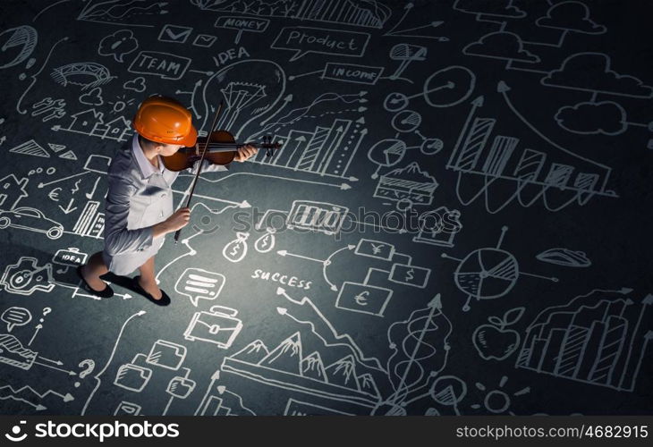 Engineer play violin. Top view of businesswoman in helmet playing violin